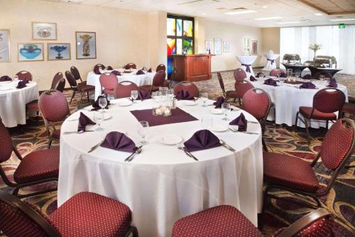 a banquet room with white tables and red chairs at Radisson Hotel Corning in Corning