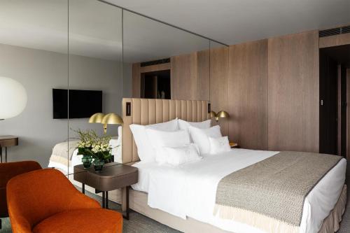 a hotel room with a large bed and a chair at Altis Porto Hotel in Porto