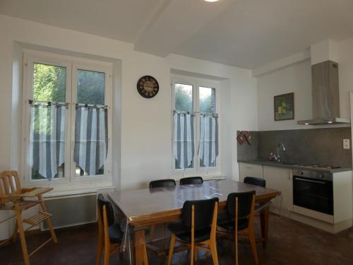 a kitchen with a table and chairs and a clock on the wall at Maison de caractère avec jardin clos, idéale pour familles, proche sentiers de randonnée - FR-1-581-88 in Nonvilliers-Grandhoux