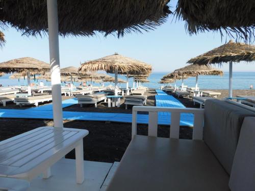 a beach with chairs and umbrellas and the ocean at Perissa BeachFront Rooms in Perissa
