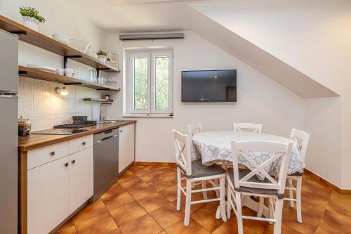 a kitchen with a table and chairs and a tv at Villa Haya with heated pool in Linardići