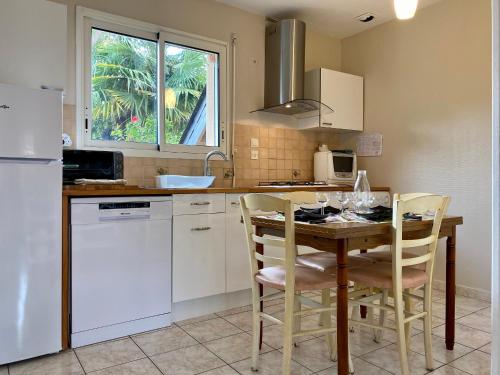 a kitchen with a wooden table with chairs and a sink at Maison au calme avec jardin clos, 25 km des plages, 2 chambres, climatisation, Wifi, parking sécurisé - FR-1-306-1225 in Pontchâteau