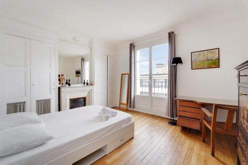 une chambre blanche avec un lit et un bureau dans l'établissement 4 chambres 120m2 - Vue Tour Eiffel a Saint-Germain, à Paris