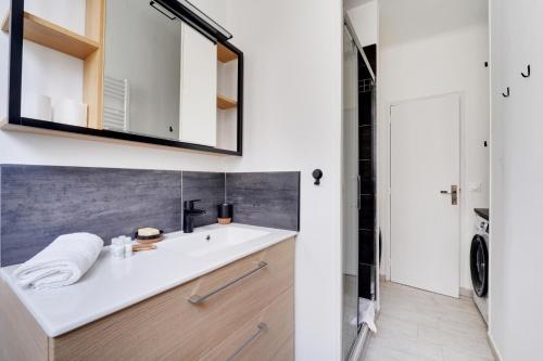 une salle de bain avec un lavabo et un miroir dans l'établissement 4 chambres 120m2 - Vue Tour Eiffel a Saint-Germain, à Paris