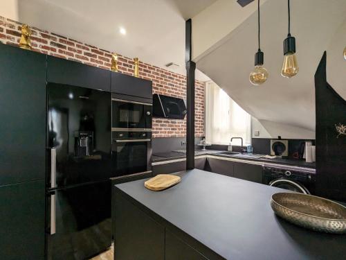 - une cuisine avec des armoires noires et un réfrigérateur noir dans l'établissement Studio Confort Centre-Ville: Cuisine Équipée, Clim, WiFi, Netflix, Proche Gare et Bus Gratuits - FR-1-591-542, à Châteauroux