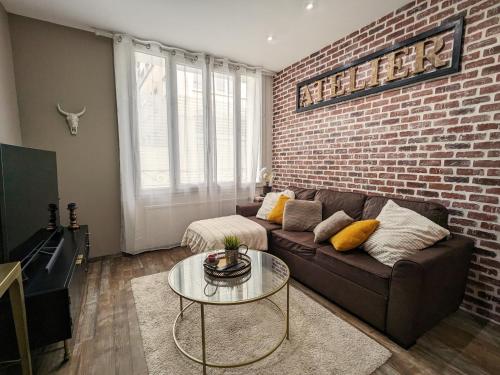 un salon avec un canapé et un mur de briques dans l'établissement Studio Confort Centre-Ville: Cuisine Équipée, Clim, WiFi, Netflix, Proche Gare et Bus Gratuits - FR-1-591-542, à Châteauroux