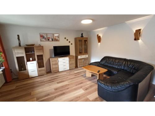 a living room with a leather couch and a table at Ferienwohnung Lidwina in Steinwiesen