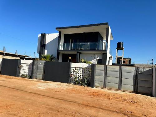 a house with a fence in front of a dirt road at Casa de Hóspedes Villa Nova in Maputo