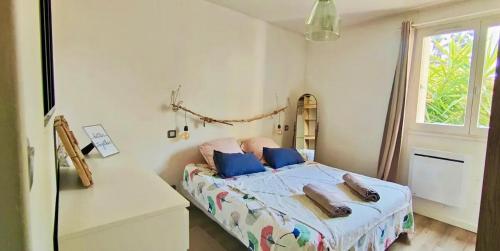 une chambre avec un lit avec des oreillers bleus et une fenêtre dans l'établissement T2 à 5 minutes des plages du Mourillon, à Toulon