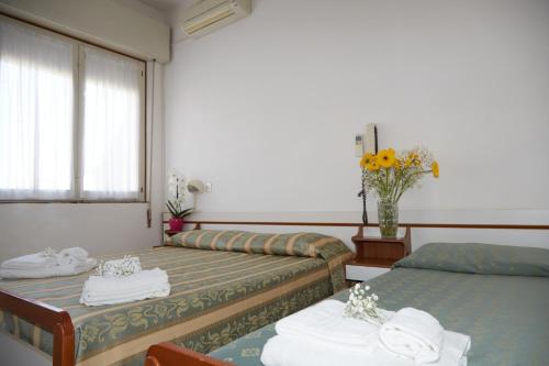 a hotel room with two beds and a vase of flowers at Hotel ITALIACERVIA in Cervia