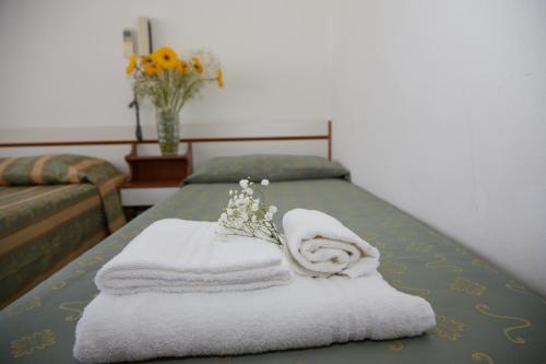a bed with towels and a vase of flowers on it at Hotel ITALIACERVIA in Cervia