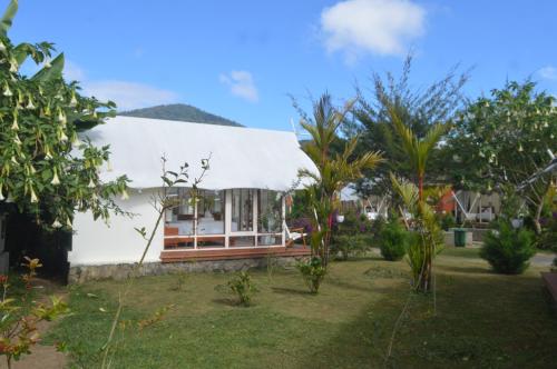 a white house with trees in front of it at Svargan Lakeside Glamping in Tabanan