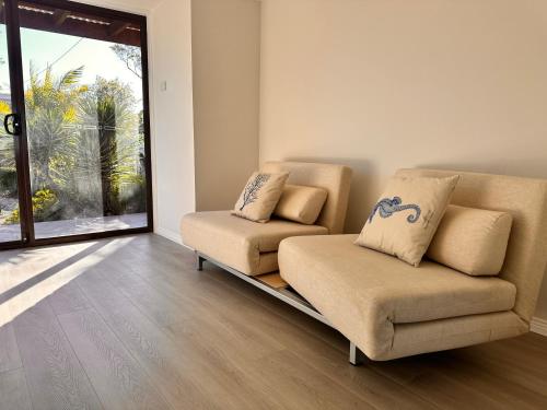 a living room with two chairs and a couch at The Pelican Palace Your Perfect Retreat Absolute waterfront, Stunning Clear Water View and Direct Access to water in Gorokan