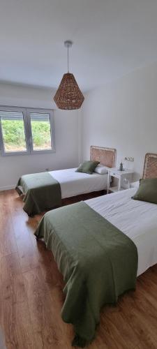 two beds in a white room with windows at Piso Boca da Ría in A Coruña