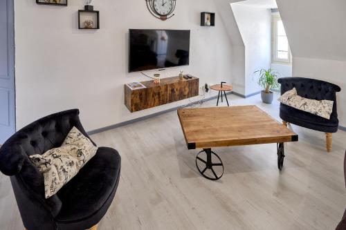 a living room with two chairs and a table and a tv at Appartement de caractère, charme in Nevers