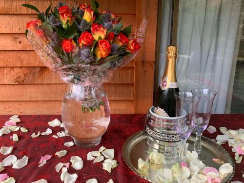 a vase of flowers on a table with a bottle of champagne at The Farmhouse B&B in Stellenbosch