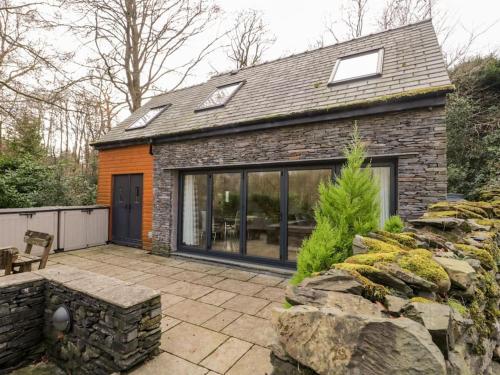 a stone house with glass doors and a patio at Bridge Cottage in Newby Bridge