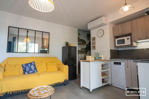 un salon avec un canapé jaune et une cuisine dans l'établissement Marina Lodge - T2 climatisé avec WIFI et piscine, à Vias