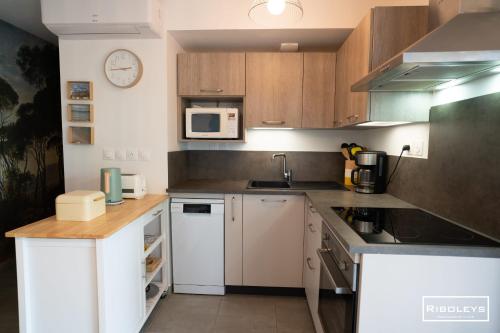 une cuisine avec des appareils électroménagers blancs et des armoires en bois dans l'établissement Marina Lodge - T2 climatisé avec WIFI et piscine, à Vias