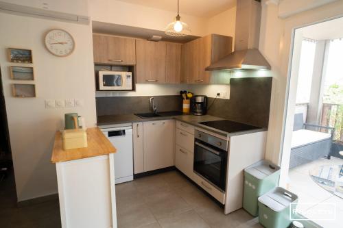 - une cuisine avec des placards en bois et des appareils blancs dans l'établissement Marina Lodge - T2 climatisé avec WIFI et piscine, à Vias