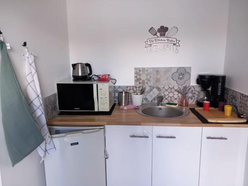 un comptoir de cuisine avec un micro-ondes et un évier dans l'établissement Petit studio independant mitoyen à la maison, à Jaunay-Clan