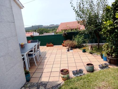 a patio with a table and chairs and potted plants at Casa de verano in O Grove