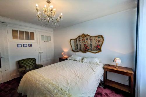 - une chambre avec un lit blanc et un lustre dans l'établissement studio au Grand Hôtel du Revard Un Voyage dans le Temps, à Pugny-Chatenod