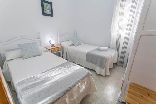 a bedroom with two beds and a table and a window at Embrujo Andaluz Complejo Rural Órgiva in Órgiva