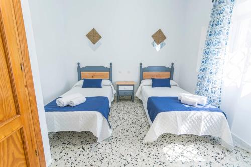 two beds in a room with blue and white at Embrujo Andaluz Complejo Rural Órgiva in Órgiva