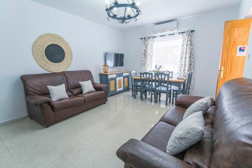a living room with two leather couches and a dining room at Embrujo Andaluz Complejo Rural Órgiva in Órgiva