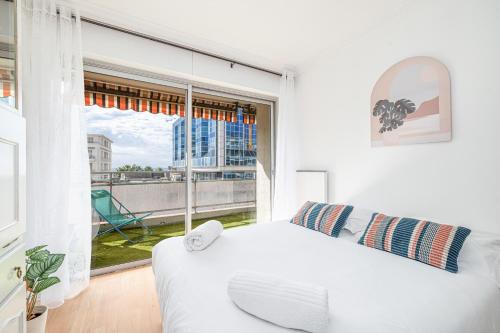 une chambre avec un lit blanc et une grande fenêtre dans l'établissement Large 2 Bdr Close to the Beach Balcony & Garage, à Nice