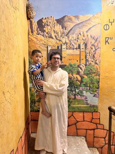 a man holding a child in front of a painting at Dar Mayssa Rose in Zawyat