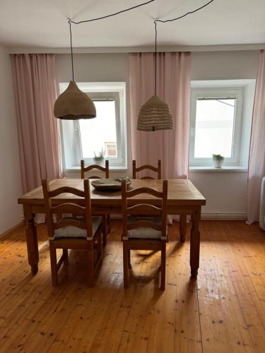 a dining room with a table and chairs and two windows at Dottore Casa in Kirchberg am Wechsel