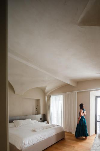 a woman in a blue dress standing next to a bed at C10 Boutique Hotel in Rome