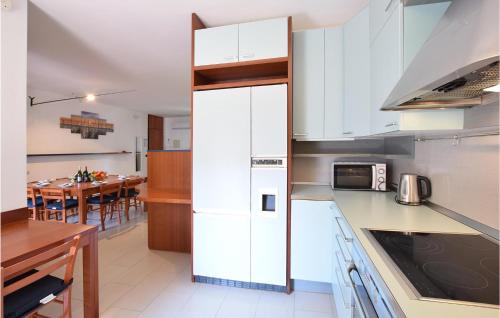 a kitchen with white cabinets and a dining room at Amazing Apartment In Lignano Sabbiadoro in Lignano Sabbiadoro