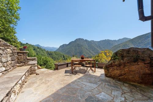 a table and chair on a patio with mountains in the background at La Libellula in Scopello