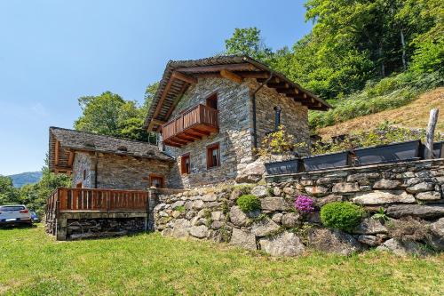 a stone house with a balcony and a stone wall at La Libellula in Scopello