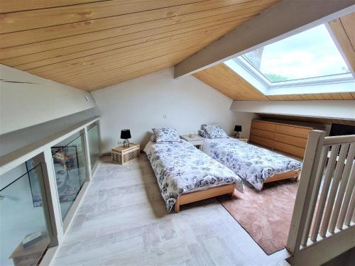 sypialnia na poddaszu z 2 łóżkami i oknem w obiekcie Appartement Cosy au Centre-Ville - Idéal pour Explorer Nancy et Verdun! - FR-1-585-84 w mieście Bar-le-Duc