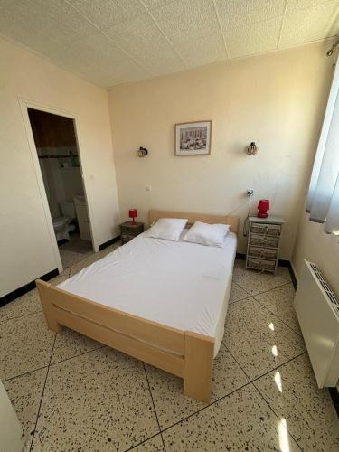 une chambre avec un grand lit dans une pièce dans l'établissement L'Arbousier, à Port-la-Nouvelle