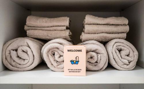 une pile de serviettes sur une étagère avec une boîte dans l'établissement Le Hyérois Studio, à Hyères