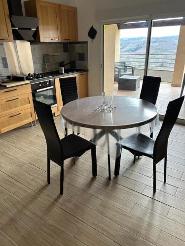 une cuisine avec une table et des chaises et une cuisine avec vue dans l'établissement le domaine du bez gite de la grise piscine sauna hammam spa, à Saint-Laurent-dʼOlt