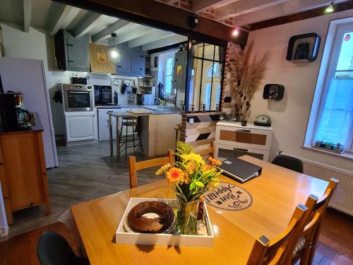 a kitchen with a table with a vase of flowers on it at Charmant gîte au cœur du Val de Loire, proche châteaux, Orléans, avec jardin et équipements complets - FR-1-590-258 in Sigloy