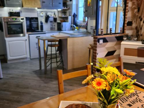 a kitchen with a table with a vase of flowers on it at Charmant gîte au cœur du Val de Loire, proche châteaux, Orléans, avec jardin et équipements complets - FR-1-590-258 in Sigloy