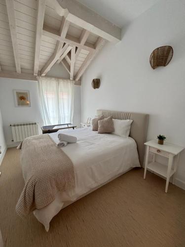 a bedroom with a large white bed and a table at Casa Rugama Chalet con piscina de temporada en el corazón de Cantabria in Arredondo