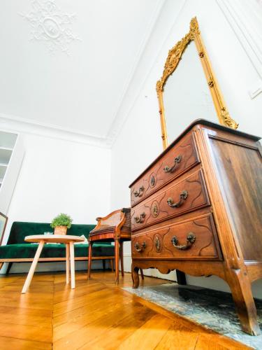 une commode en bois dans une pièce avec un canapé vert dans l'établissement Heart of Paris - Chic et Cosy - opéra, à Paris