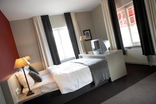 a bedroom with a bed and a tv and windows at Hotel De Prins in Sittard