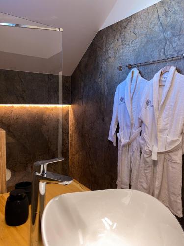 a bathroom with a sink and a white robe at Altfel Bran Chalet 1 in Bran