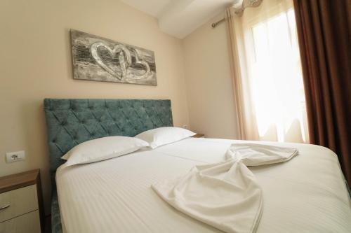 a bedroom with a bed with white sheets and a window at Haris Apartments Tirana in Tirana