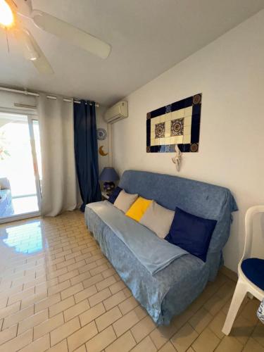 un salon avec un canapé bleu dans une pièce dans l'établissement T2 Mer et Soleil avec Terrasse, à Sète