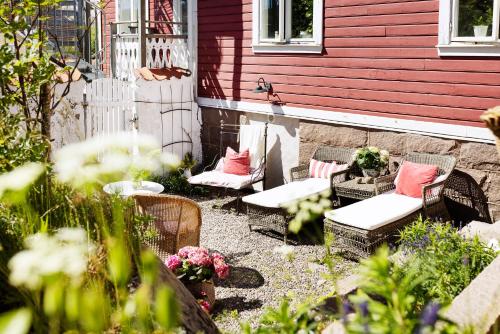 a patio with chairs and tables and a red house at Strandflickornas Havshotell Lysekil in Lysekil